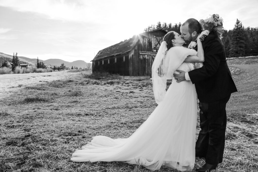 You May Kiss The Bride - Bride and groom kissing in front of an old barn at sunset