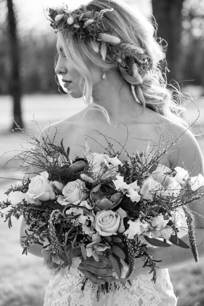 blond bohemian bride holding bouquet of flowers in the sunlight