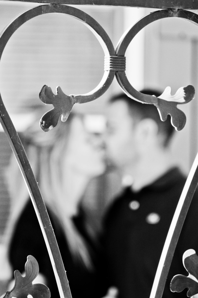 couple kissing behind ironwork heart