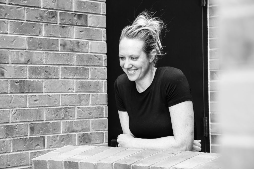 Blond woman in black t shirt laughing in the city