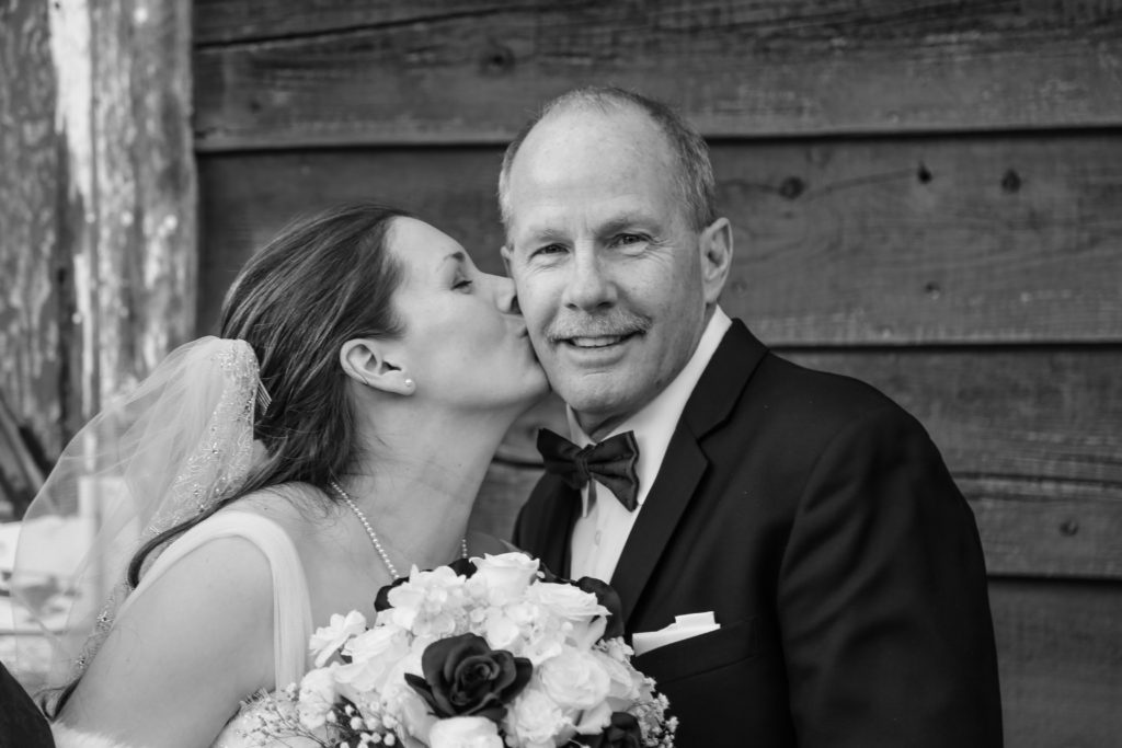 Bride giving a kiss on the cheek to the father of the bride