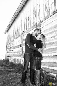 Couple kissing in front of old white barn