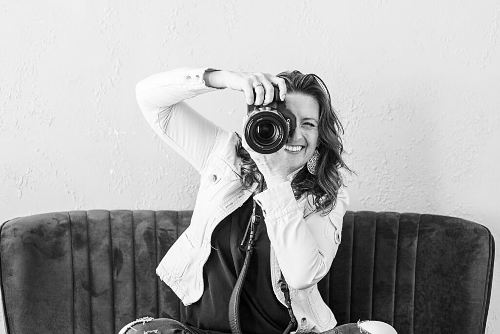 photographer Ashlee Bratton sitting cross legged on a couch shooting her camera