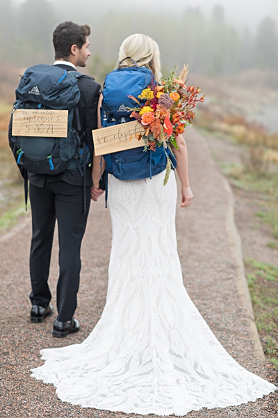 Bride and groom eloping with hiking backpacks in the mountains