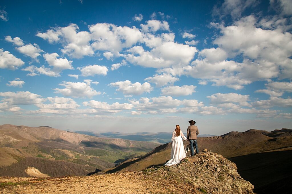 bride and groom holding hands on a mountain top