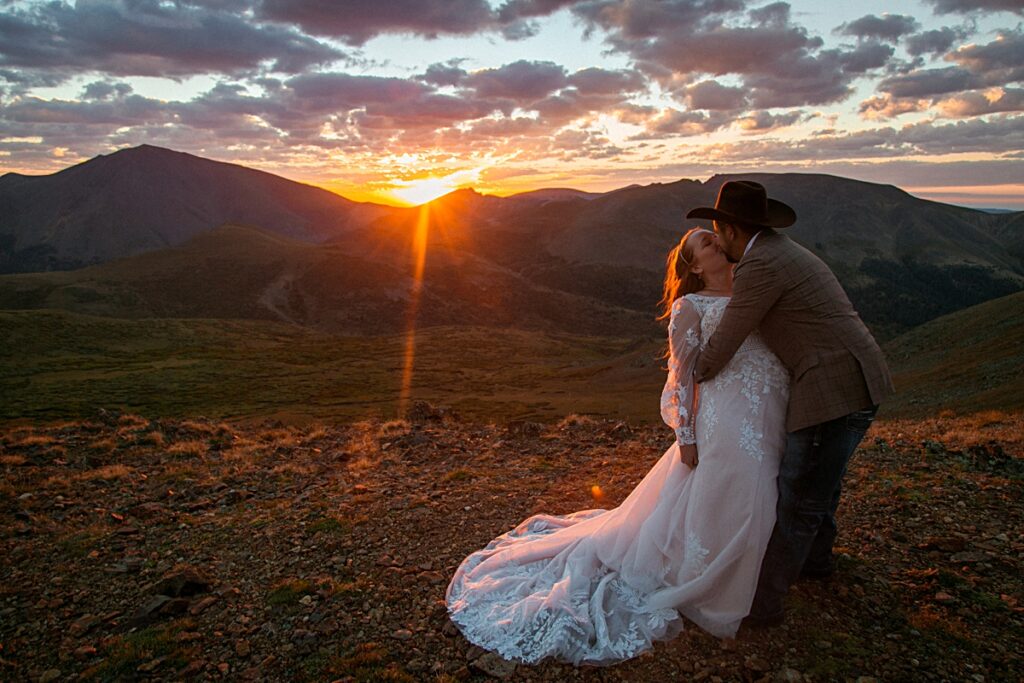 sunrise dip kiss of bride and groom in Colorado's Rocky Mountains